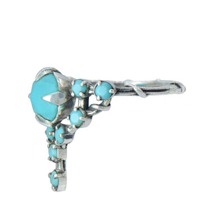 A Karen Karch silver cocktail ring featuring a large round turquoise center stone surrounded by smaller turquoise stones, in a star-like formation, side view.