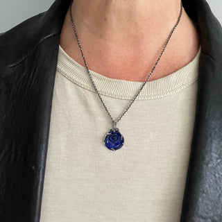 Karen Karch Silver carved Lapis Rosebud Charm set in silver claws hanging on a vine detailed bail on a chain shown on a person's neck.