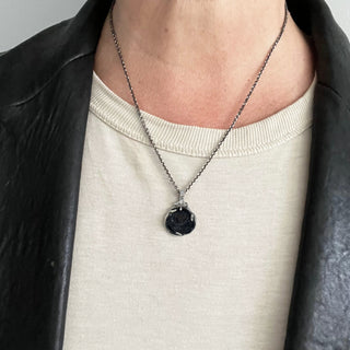 Karen Karch Carved Black Onyx rose bud amulet with silver claw setting on a chain on a person's neck. 