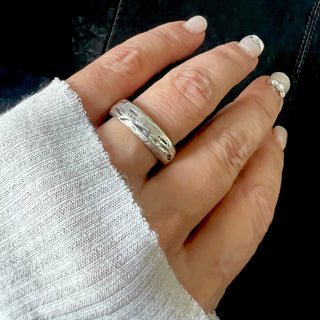 A Karen Karch silver domed weathered band with an irregular rounded edge on a hand. 