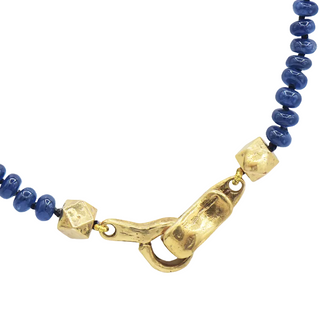 A close up of the gold clasp on a Karen Karch Necklace with blue sapphire beads on a white background.