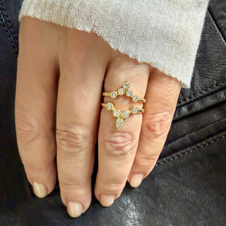 Karen Karch 18k yellow gold tiara ring comparison, both featuring bezel-set round diamonds arranged to create a "v" shape. The configuration is crowned with an outward pointing pear-shape bezel. Shown on a hand.