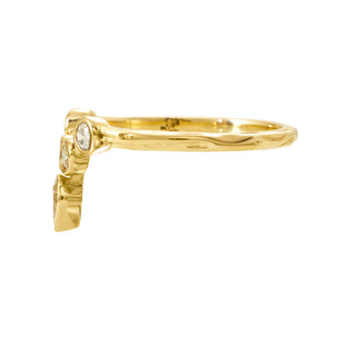 Side view of a Karen Karch 18k yellow gold tiara ring featuring bezel-set round diamonds arranged to create a "v" shape. This configuration is crowned with an outward pointing pear-shape bezel. The weathered precious metal shank measures 1.6mm.