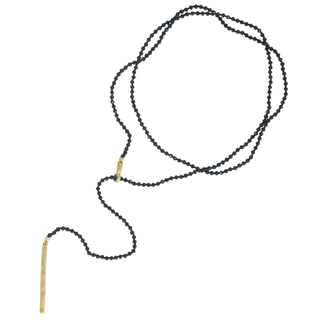 A black spinel gold lariat necklace with a weathered texture closure, featuring a loop and a pull-through bar.