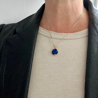 Karen Karch 14k Gold pendant with a Lapis blue rose design on a vine detailed bail on a chain on a person