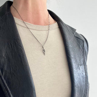 Karen Karch by Deme Wolfe Silver Little Victory wing charm on chain on person in leaather jacket