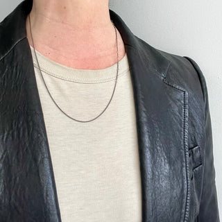 A person wearing a Karen Karch by Deme Wolfe Mystical Bling Silver chain necklace featuring two different chain styles merged