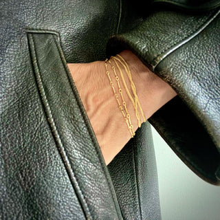 A person's wrist wearing a Karen Karch by Deme Wolfe gold-filled elongated mystical bling wrap chain, which is designed to be wrapped around the wrist as a bracelet.