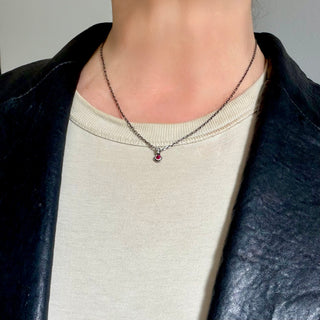 Karen Karch Silver Charm Necklace with a small round red ruby gemstone pendant on a thin chain on a person.