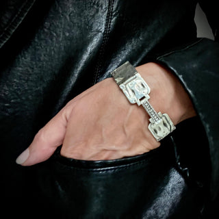 A 20mm wide weathered silver bracelet with a studded clasp featuring black and white diamonds, designed by Karen Karch on a person's wrist.