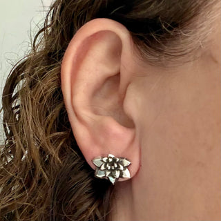 Karen Karch by Deme Wolfe pair of silver flower-shaped earrings on an ear.