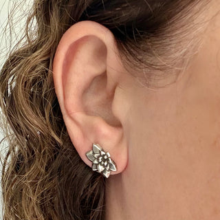 Karen Karch by Deme Wolfe pair of silver flower-shaped stud earring angled on an ear.