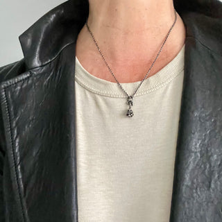 Karen Karch Reminiscent Rose Silver rosebud charm with a twining vine that forms a loop ending in an emerald on a chain on a person