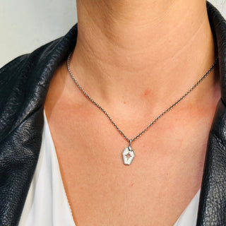 Karen Karch by Deme Wolfe silver tag with a cut-out star design, accented by a snake with a raised diamond texture that wraps along the side edge and curves up to the bail, which finishes with the snake's head on a chain on a person.