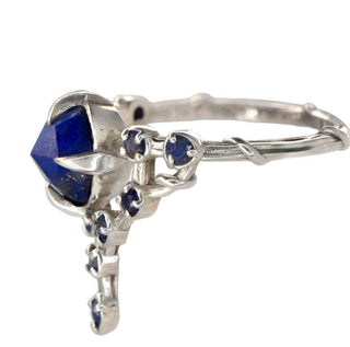 A Karen Karch silver cocktail ring featuring a large round lapis center stone surrounded by smaller lapis stones, in a star-like formation, side view on white background.