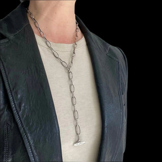 A person wearing a Karen Karch Sterling Silver Textured Toggle Oval Chain Link Necklace designed to be worn in a lariat shape