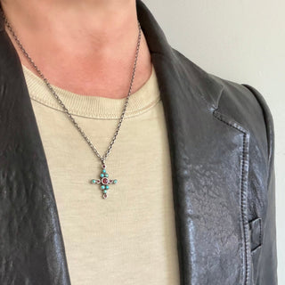 Karen Karch Star-crossed silver Cross amulet pendant created from clus\tered beel set turquoise and red sapphires on a person.