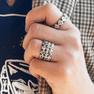 Karen Karch Outshine Weathered 3mm, 4mm, 5mm Stacked silver band with a 6mm on pointer finger, textured, angular repeating pattern design on white background.