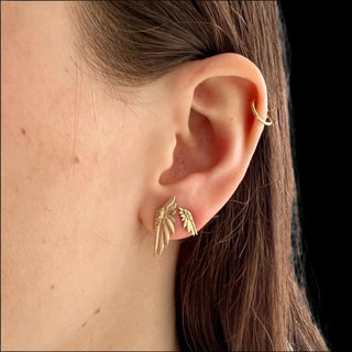 Karen Karch pair of gold earrings designed with a detailed wing motif, one larger and one smaller paired together on the ear inspired by the mysticism of the desert.