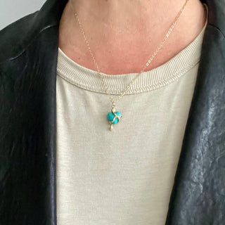 Karen Karch by Deme Wolfe Serpentine Love Turquoise Heart embraced by a 10k yellow gold snake on a gold filled chain on a person in black leather jacket. 