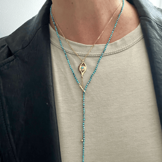 A turquoise and gold beaded lariat necklace with a loop and pull-through bar closure layered with Evil Ey by Karen Karch