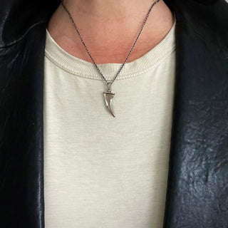 KAREN KARCH Silver Unearthed Textured Lucky Horn on chain on person in leather jacket
