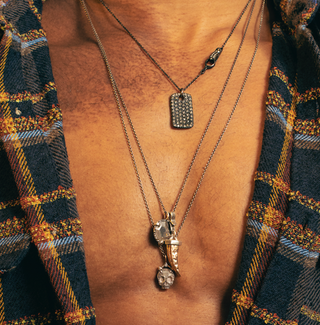 Karen Karch by Deme Wolfe Silver Skull pendant with raised silver shapes and a mini crown layered with various other charms and a diamond dog tag. 
