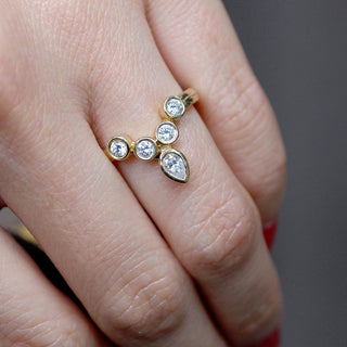 Karen Karch Turned Out invincible Tiara Ring in yellow gold with 4 round diamond arranged to form a v-shape with a pear shape diamond at its end with point facing outward on Finger. 