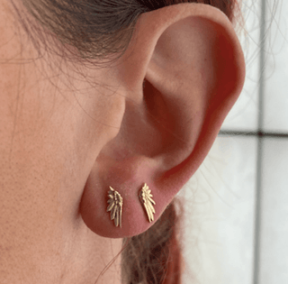 Karen Karch by Deme Wolfe 10k rose gold stud earrings with a mini wing design paired on one ear